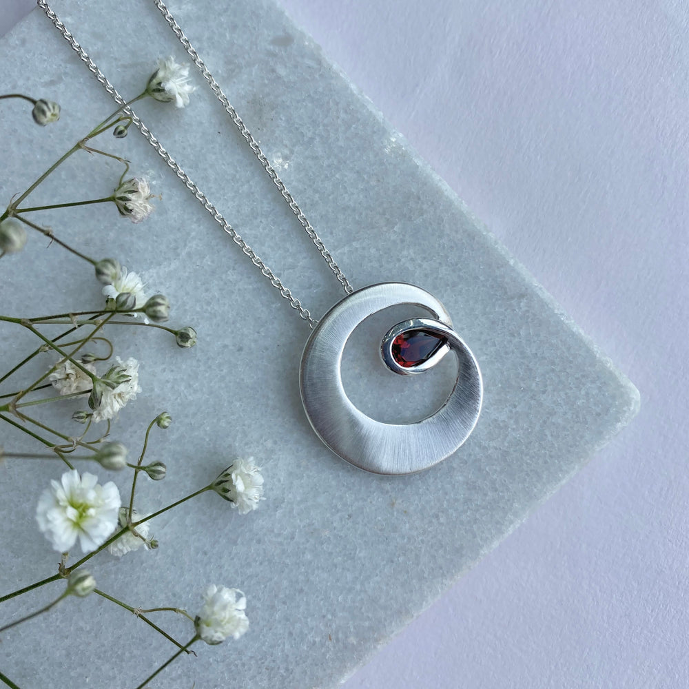 Silver Matt finish Circle Swirl Pendant Set With a Pear Shaped Garnet