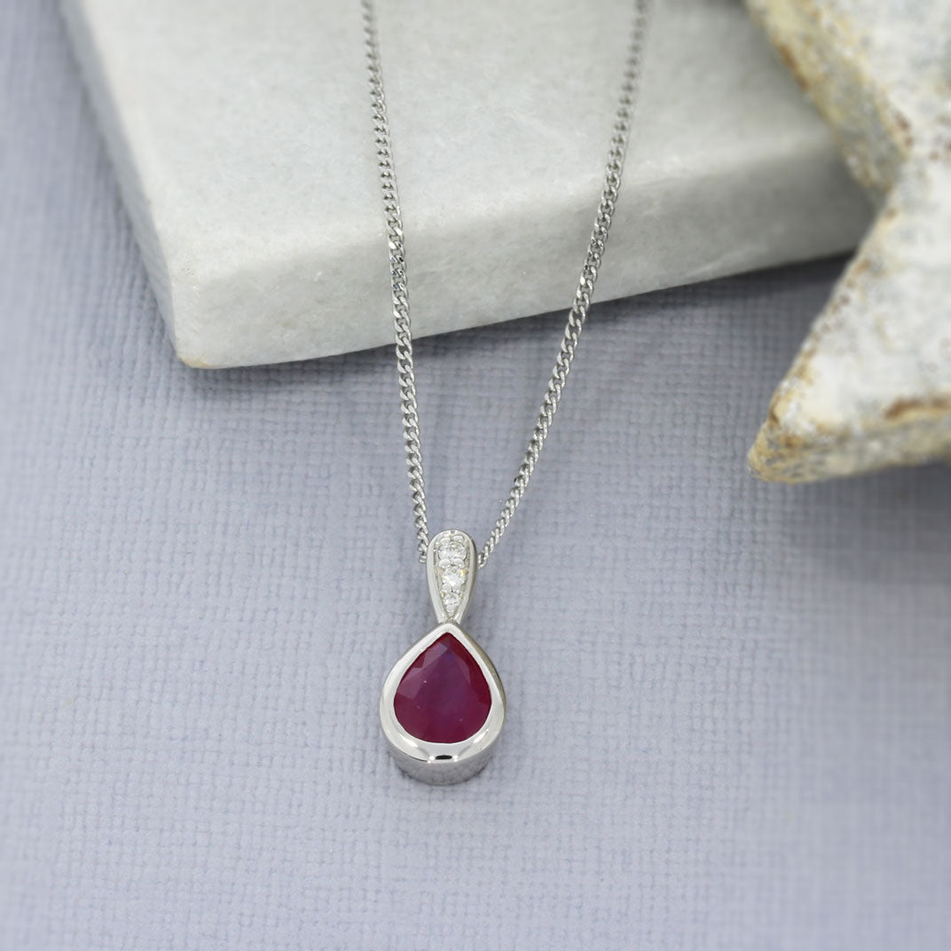 9ct White Pear Shape Ruby Pendant With Diamond Set Bale & Chain