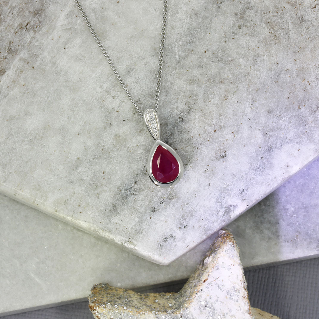 9ct White Pear Shape Ruby Pendant With Diamond Set Bale & Chain